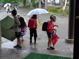 傘の水をはらって入る児童たちの画像
