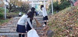 手長神社の石段の落ち葉を集める生徒たちの画像