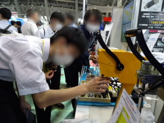 企業の方に促され、機械を触って確かめる生徒