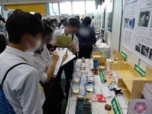 教育委員会のブースで他校の代表作品を見て感心している生徒たち